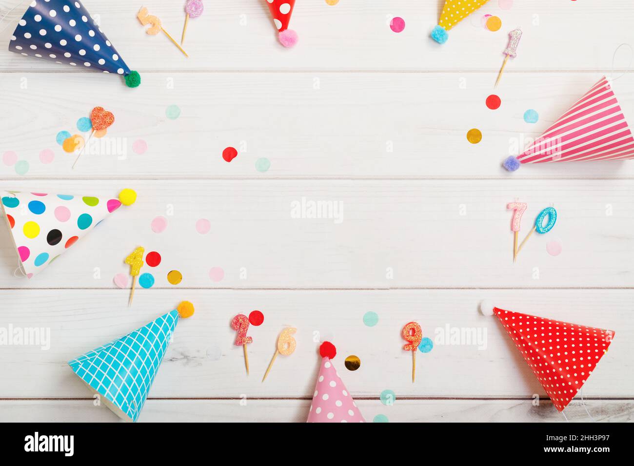 Cappello colorato da festa adagiato su un tavolo di legno. Compleanno, concetto di vacanza. Foto Stock