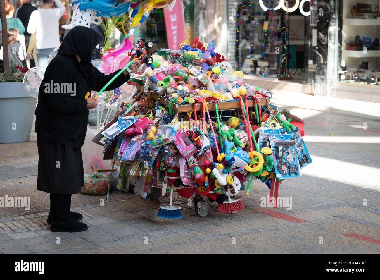 Donna anziana che vende giocattoli per bambini per le strade. Nonna che indossa panni neri funzionanti. Nicosia Cipro Foto Stock
