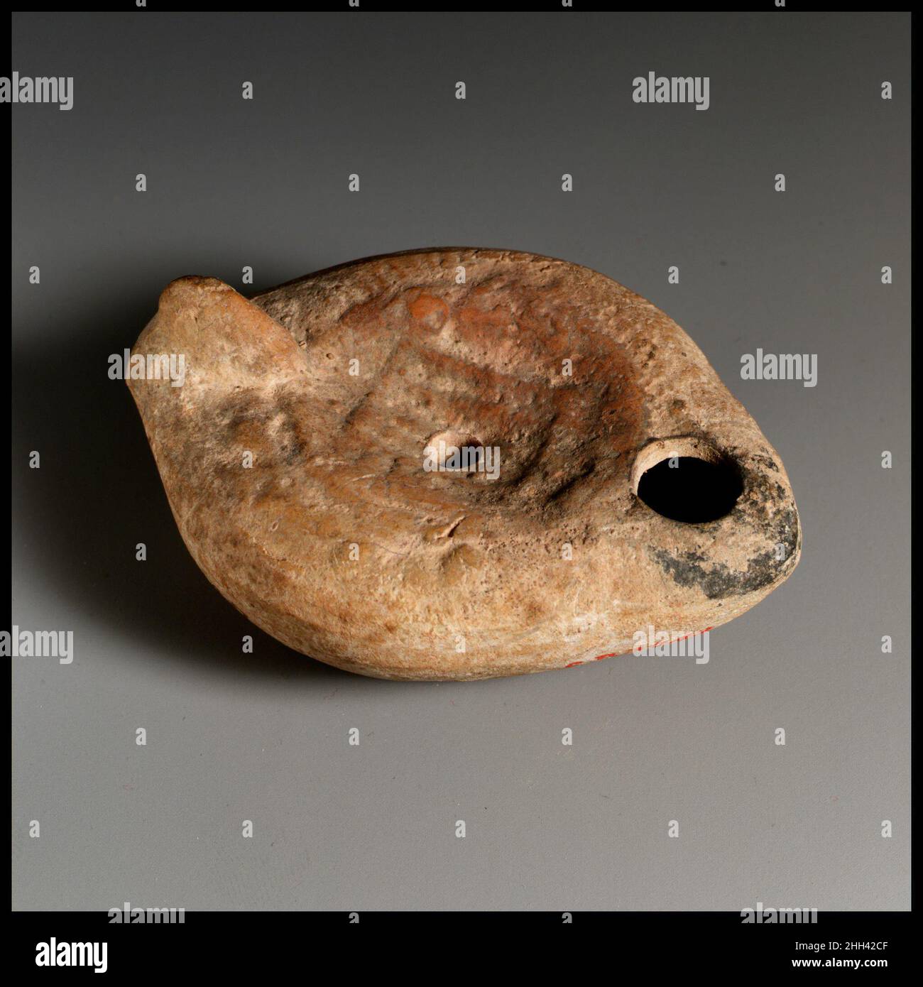 Lampada ad olio di terracotta 4th–5th secolo d.C. romana, cipriota Vessberg tipo 18. Impugnatura non forata. Realizzato in stampo. Discus: Bestiarius usando la coclea grande per proteggerlo da un orso; lettere in rilievo sotto la coclea. Spalla: Lato destro, corona di aringhe; lato sinistro, lupo (?) corsa verso l'uomo con le braccia sollevate. Sulla base concava, cerchio di lettere greche in rilievo: EYTYXHTOC.. Lampada ad olio di terracotta. Romano, cipriota. 4th–5th secolo d.C.. Terracotta. Tardo imperiale. Terracotte Foto Stock