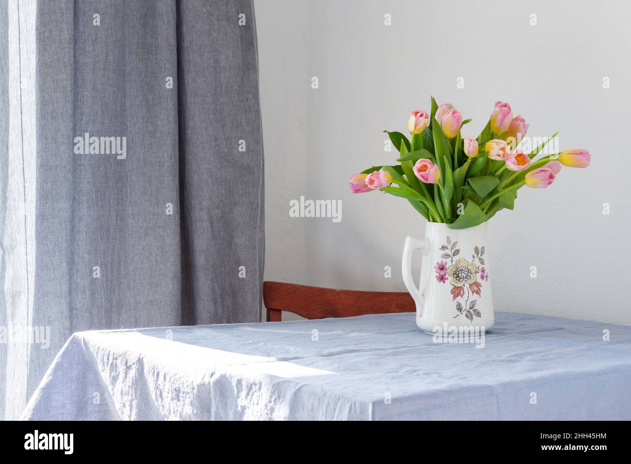 Bel bouquet primaverile di tulipani rosa in una brocca sul tavolo, fiori in un interno casa Foto Stock