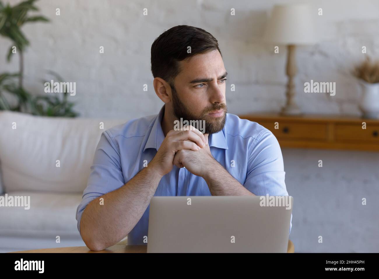 Un uomo d'affari serio e attento che lavora al tavolo con un notebook Foto Stock