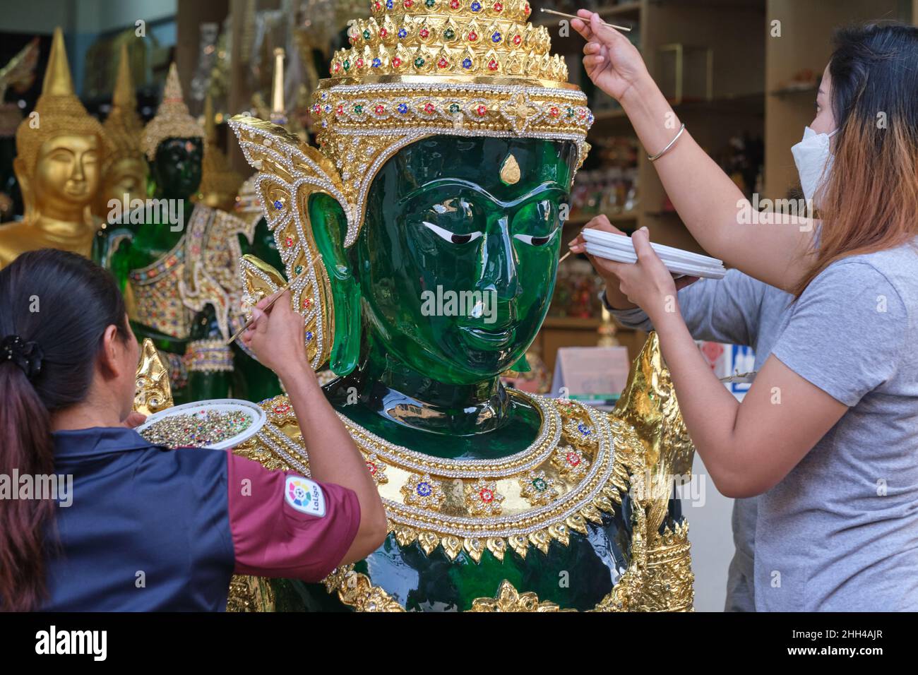 Dipendenti in un workshop per oggetti rituali buddisti a Bambung Muang Rd., Bangkok, Thailandia, mettendo i ritocchi finali ad una replica del Buddha di Giada Foto Stock