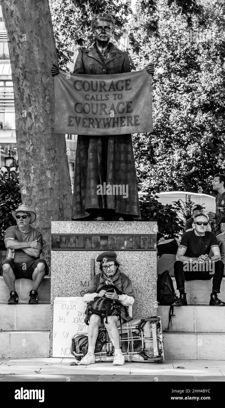 Il manifestante si riposa sotto la Statua del Millicent Fawcett nella piazza del Parlamento di Londra. Foto Stock