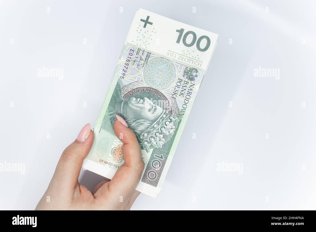 Cento zloty - banconota polacca. Valuta polacca tenuta in mano su sfondo bianco Foto Stock