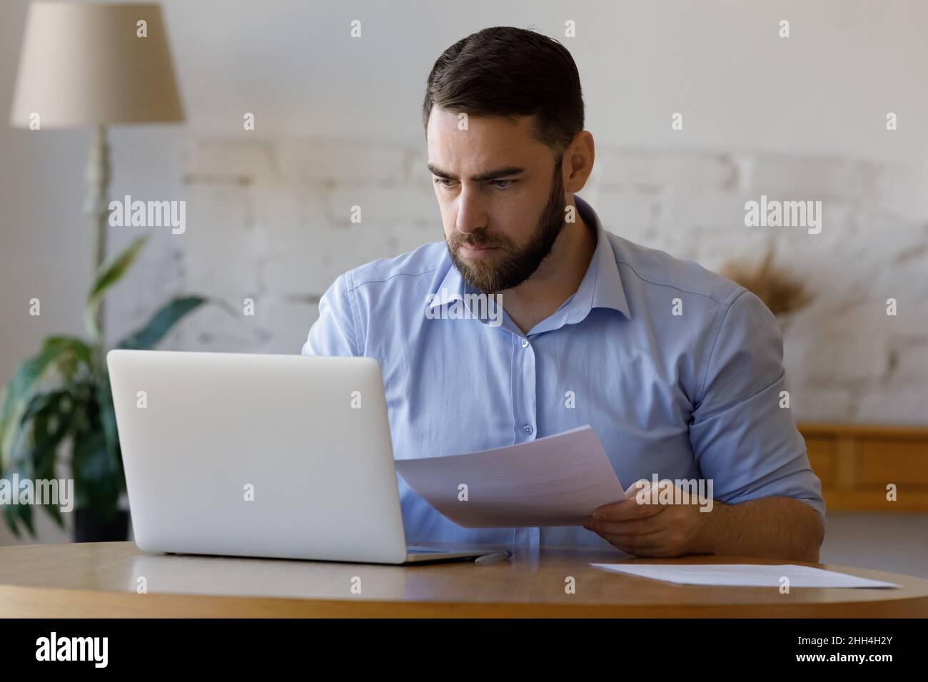 Business man incentrato sui millenni che controlla i report cartacei Foto Stock