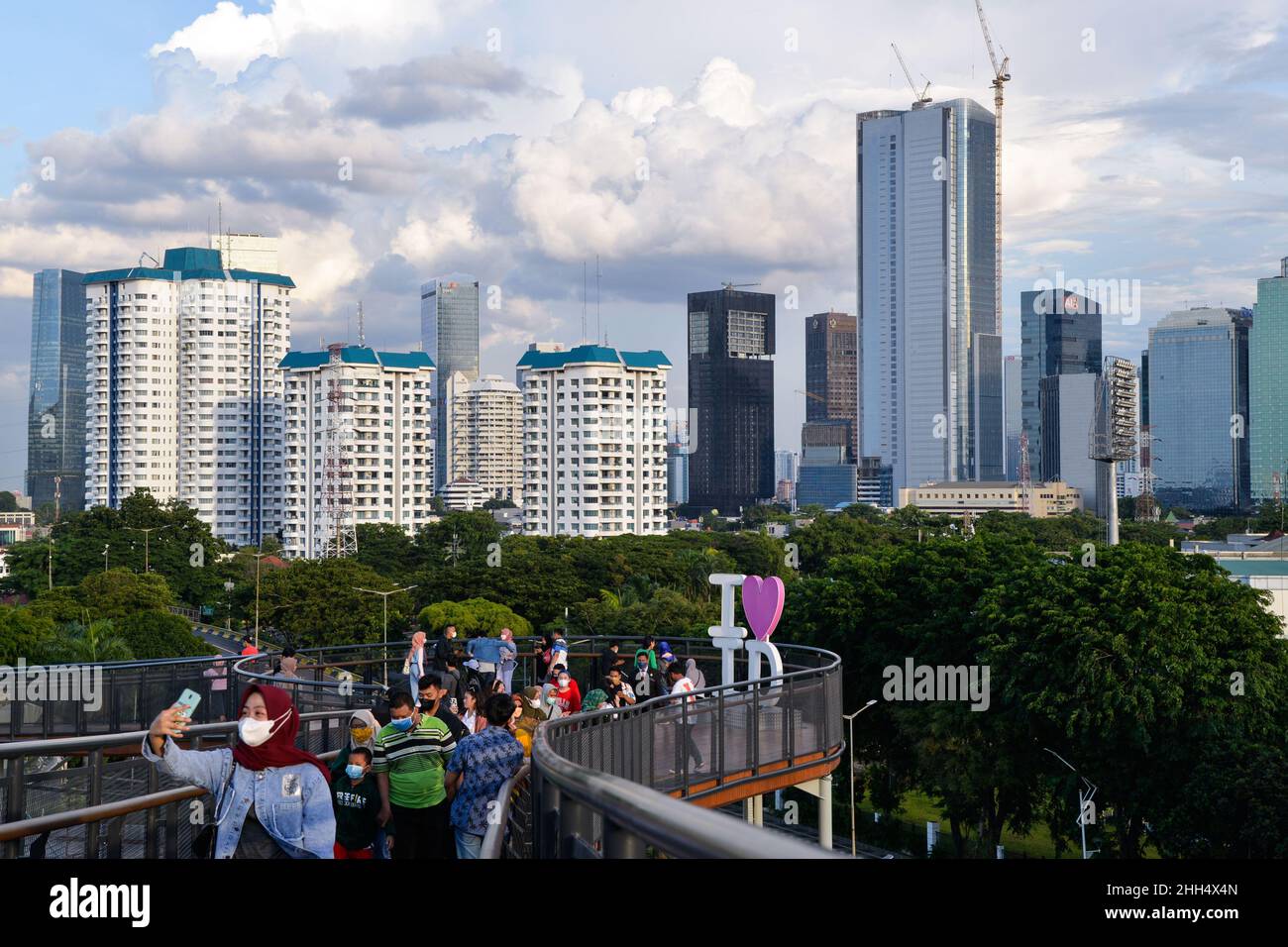 (220123) -- JAKARTA, 23 gennaio 2022 (Xinhua) -- la gente gode della vista della città sullo skywalk del parco di Senayan in Jakarta, Indonesia, 23 gennaio 2022. I legislatori indonesiani il 18 gennaio hanno approvato una legge sulla delocalizzazione della capitale della nazione nell'isola di Kalimantan, che il paese condivide i confini con la Malesia e Brunei, dall'isola più popolata di Java. Nusantara, che viene chiamata la nuova capitale, sarà costruita in due distretti a Kalimantan Est - Penajam Paser Utara e Kutai Kartanegara. Si prevede di occupare circa 256.000 ettari di terreno. Nusantara sarà il centro del governo, Whi Foto Stock
