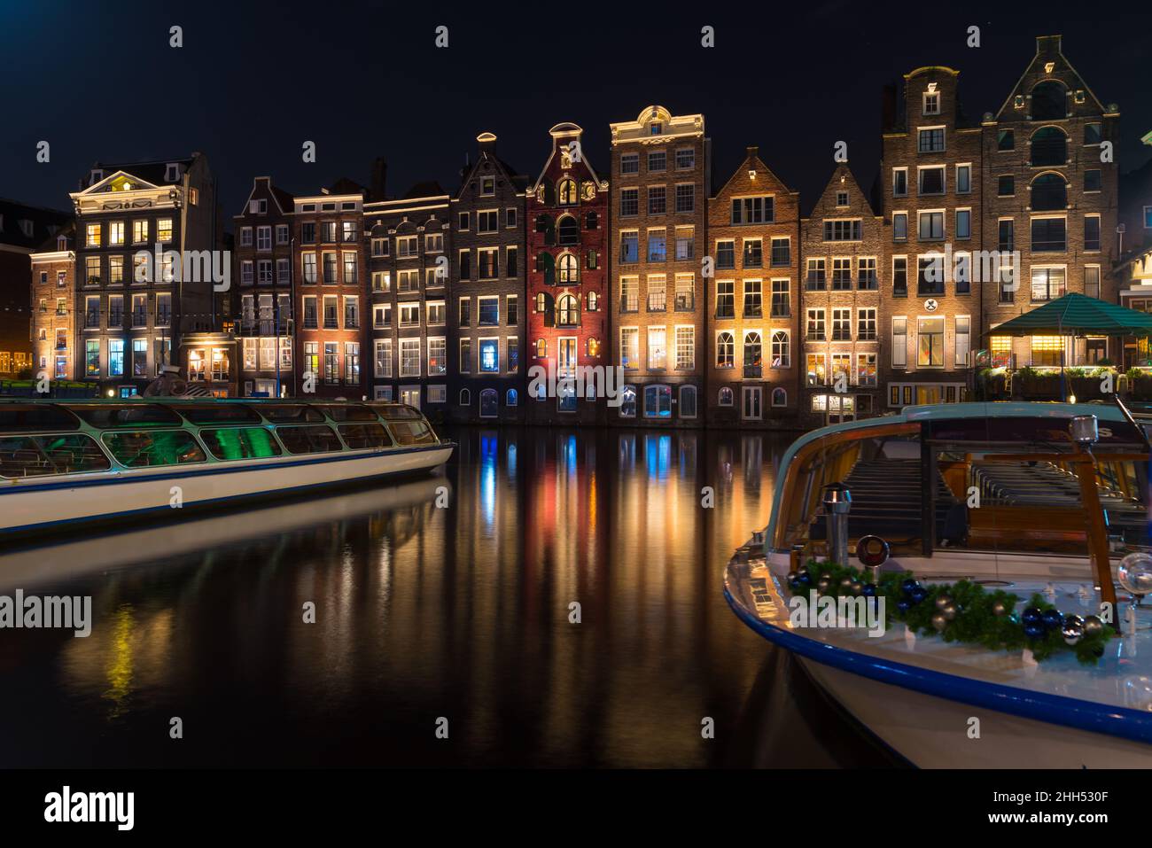 AMSTERDAM - 14 DICEMBRE 2019: Le famose case dei canali danzanti al canale Damrak di notte Foto Stock