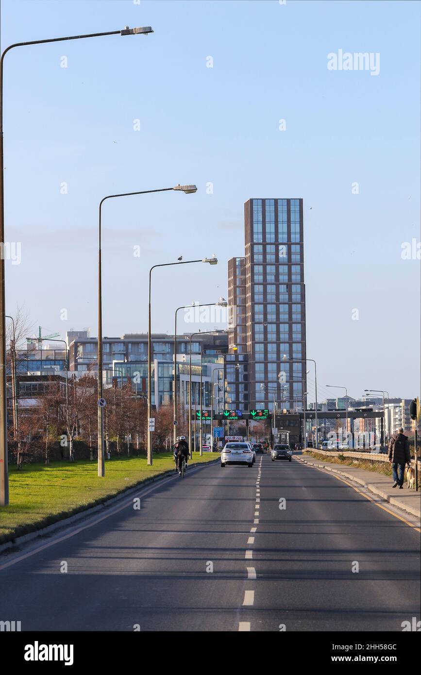 Auto e ciclisti sul ponte a pedaggio East-link 'Tom Clarke' con l'edificio Capital Dock. Bridge era usato per attraversare il fiume Liffey. Dublino, Irlanda Foto Stock