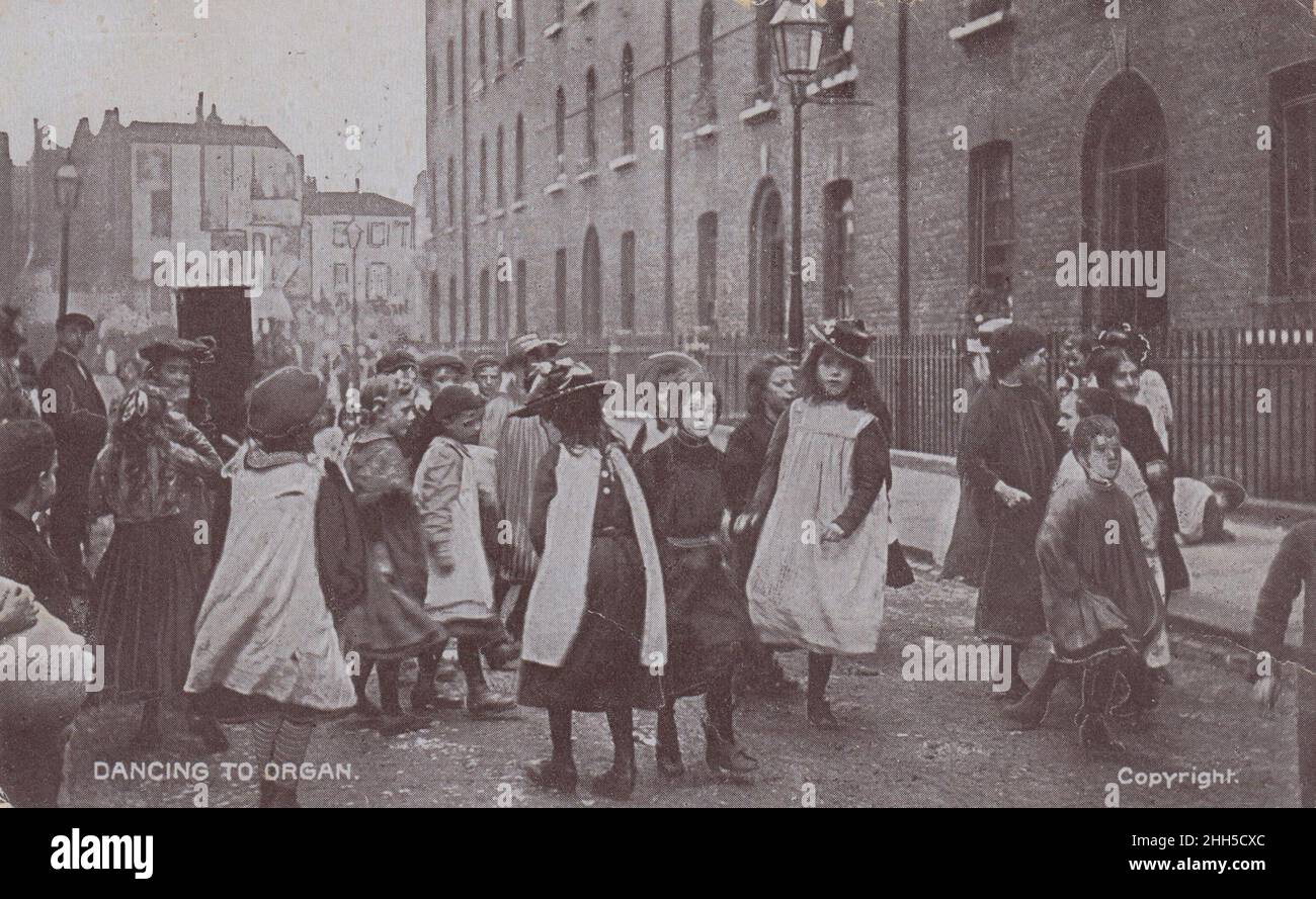 Gruppo di bambini edoardiani che ballano con un organo a botte in una strada di East London. La cartolina è stata inviata nel 1907 Foto Stock