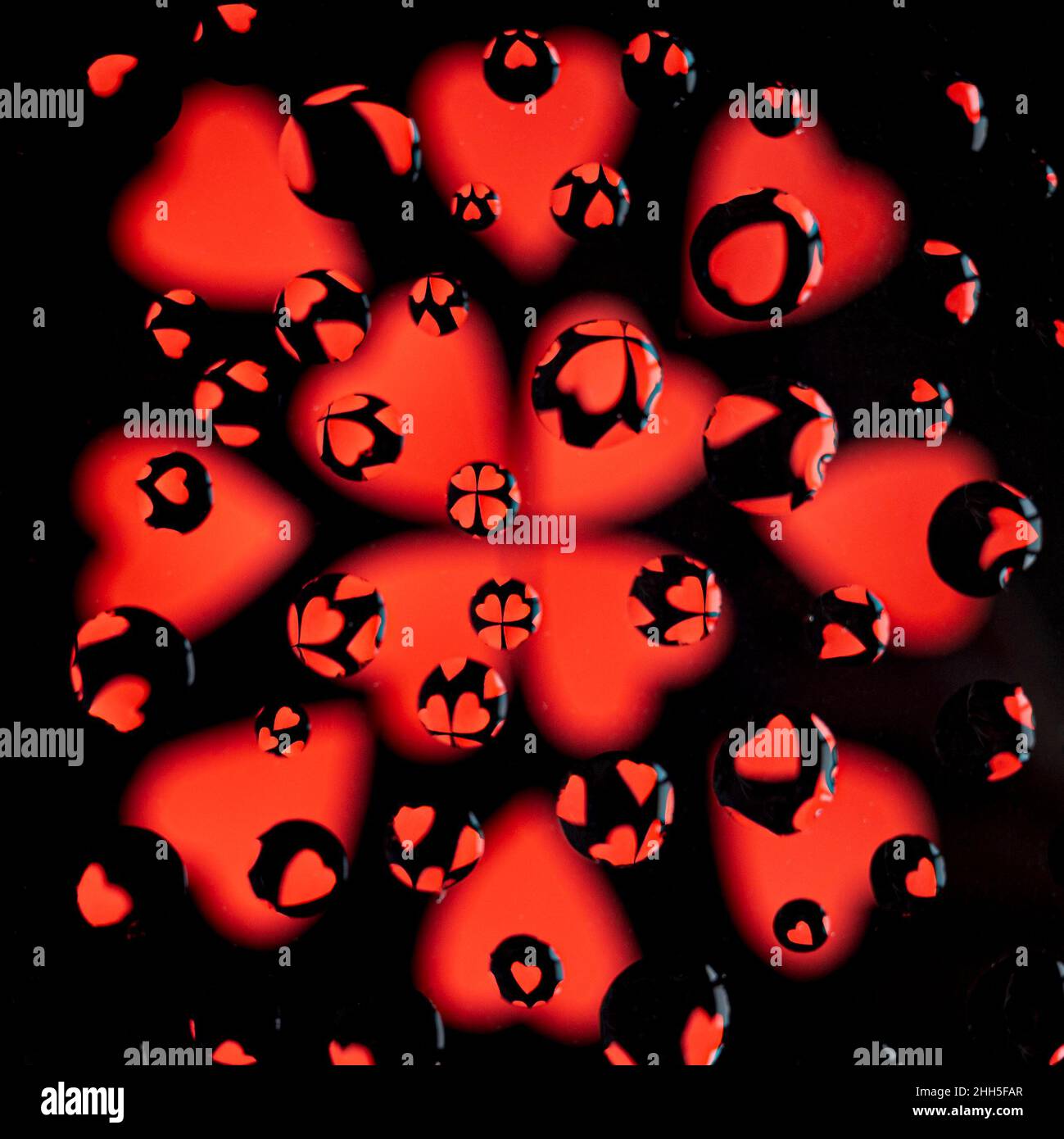 Cuori rossi su sfondo nero dietro il vetro con gocce di pioggia Foto Stock