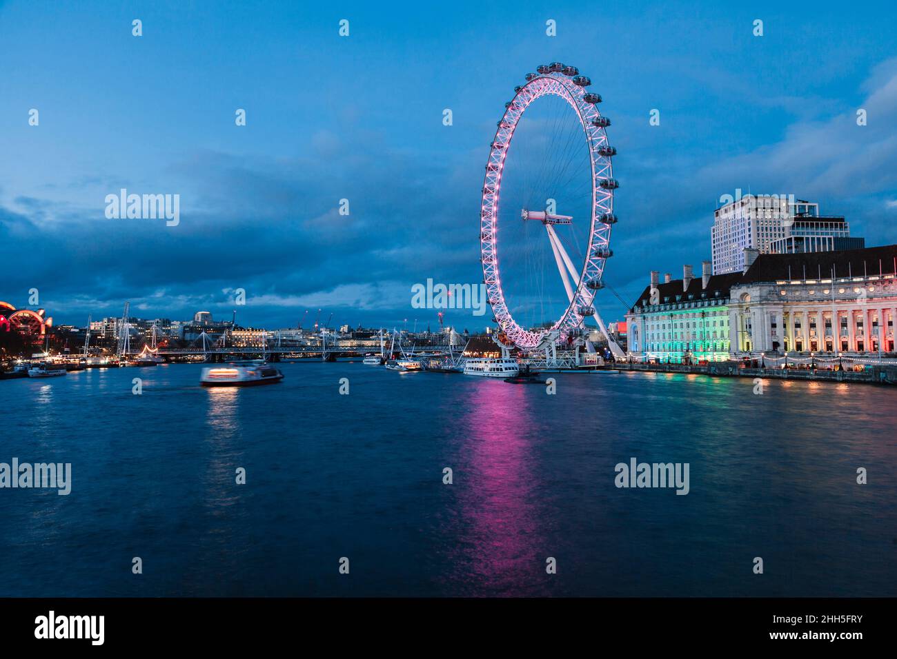 Millennium Wheel illuminata dalla riva del Tamigi in città al crepuscolo, Londra, Inghilterra, Regno Unito Foto Stock
