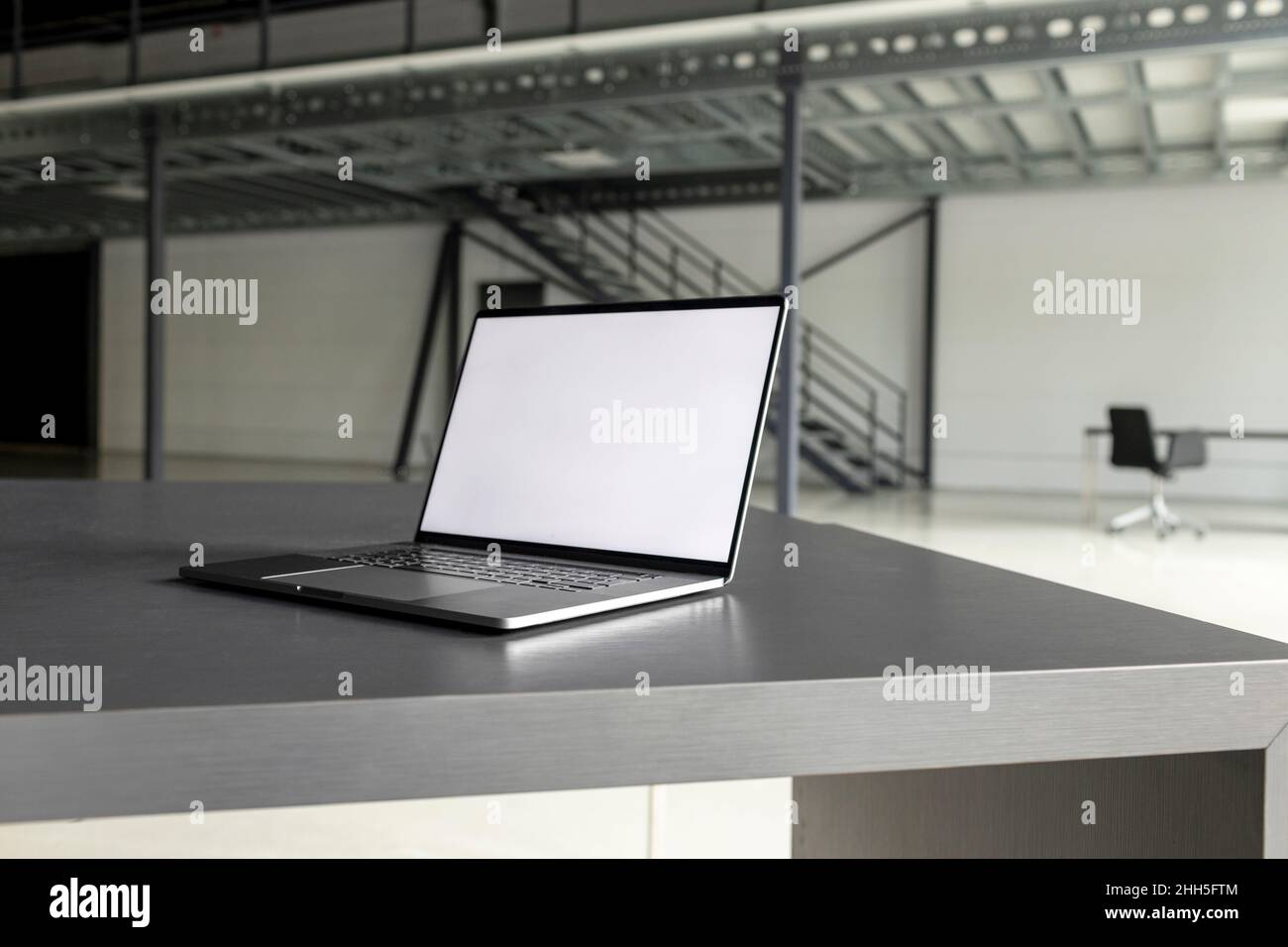 Computer portatile con schermo vuoto alla scrivania nella sala indusziale Foto Stock