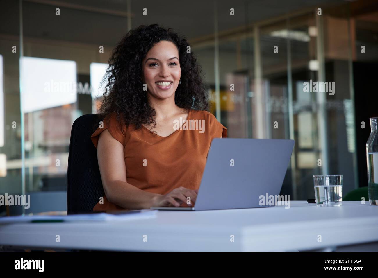 Donna d'affari felice con il laptop sulla scrivania sul posto di lavoro Foto Stock