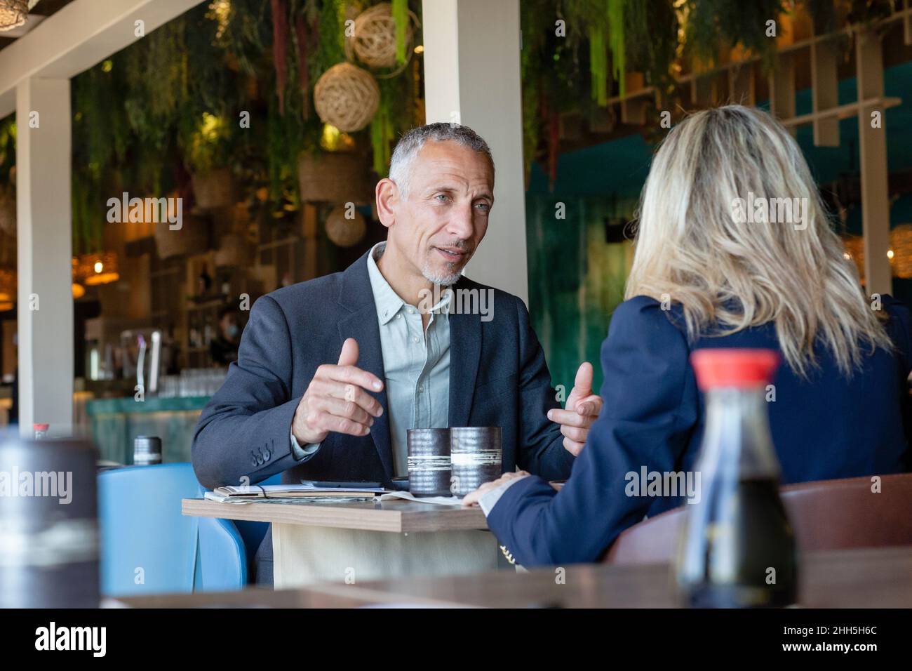 Uomo d'affari gesturing parlare con il cliente in ristorante Foto Stock