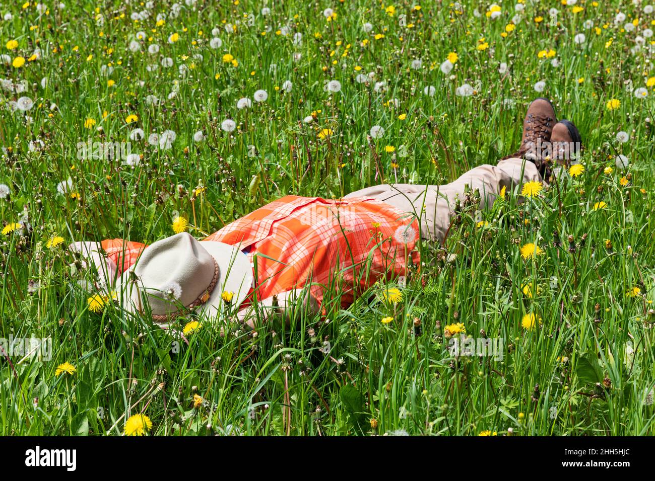 Uomo che dorme sull'erba con cappello sopra la faccia al prato Foto Stock