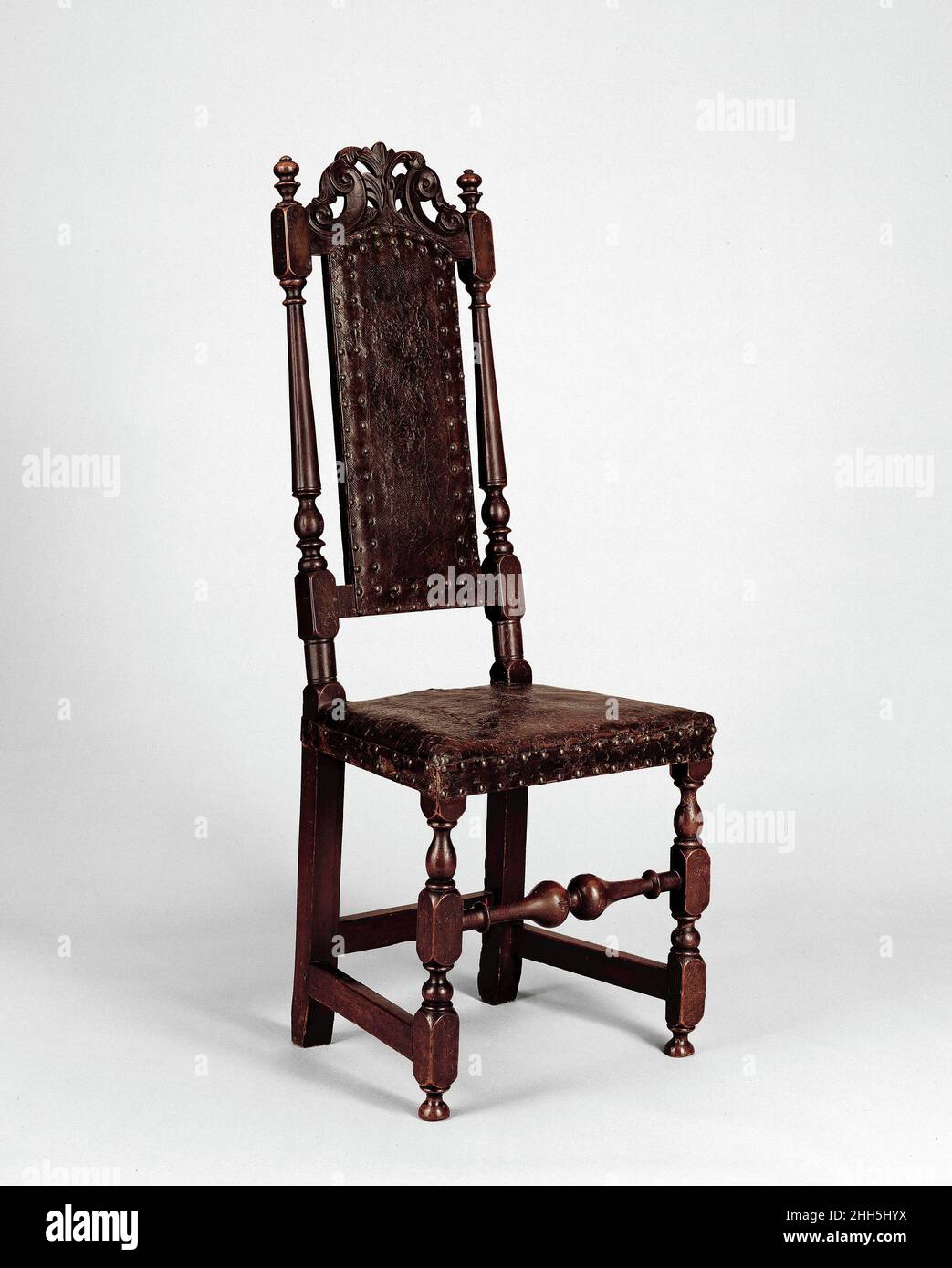 Sedia laterale 1700–1720 American Tall, maestosa e rivestita in pelle originale 'Russia', questa sedia con schienale alto è un ottimo esempio dello stile completamente sviluppato William e Mary. E' incoronata da una caratteristica ferrovia a cresta della scuola di Boston con rotoli a C e fogliame. La pelle di vitello è del tipo fatto nei pressi di San Pietroburgo nei secoli XVII e XVIII. Di solito tinto rosso e goffrato con un piccolo reticolo modello, è stato conciato e vestito con estratti di corteccia e oli per renderlo flessibile e meno soggetto a decadimento e infestazione di insetti.. Sedia laterale 1621 Foto Stock