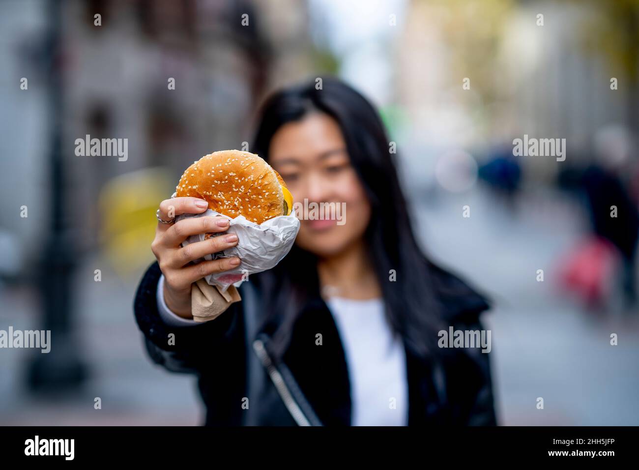 Giovane donna con hamburger in mano Foto Stock