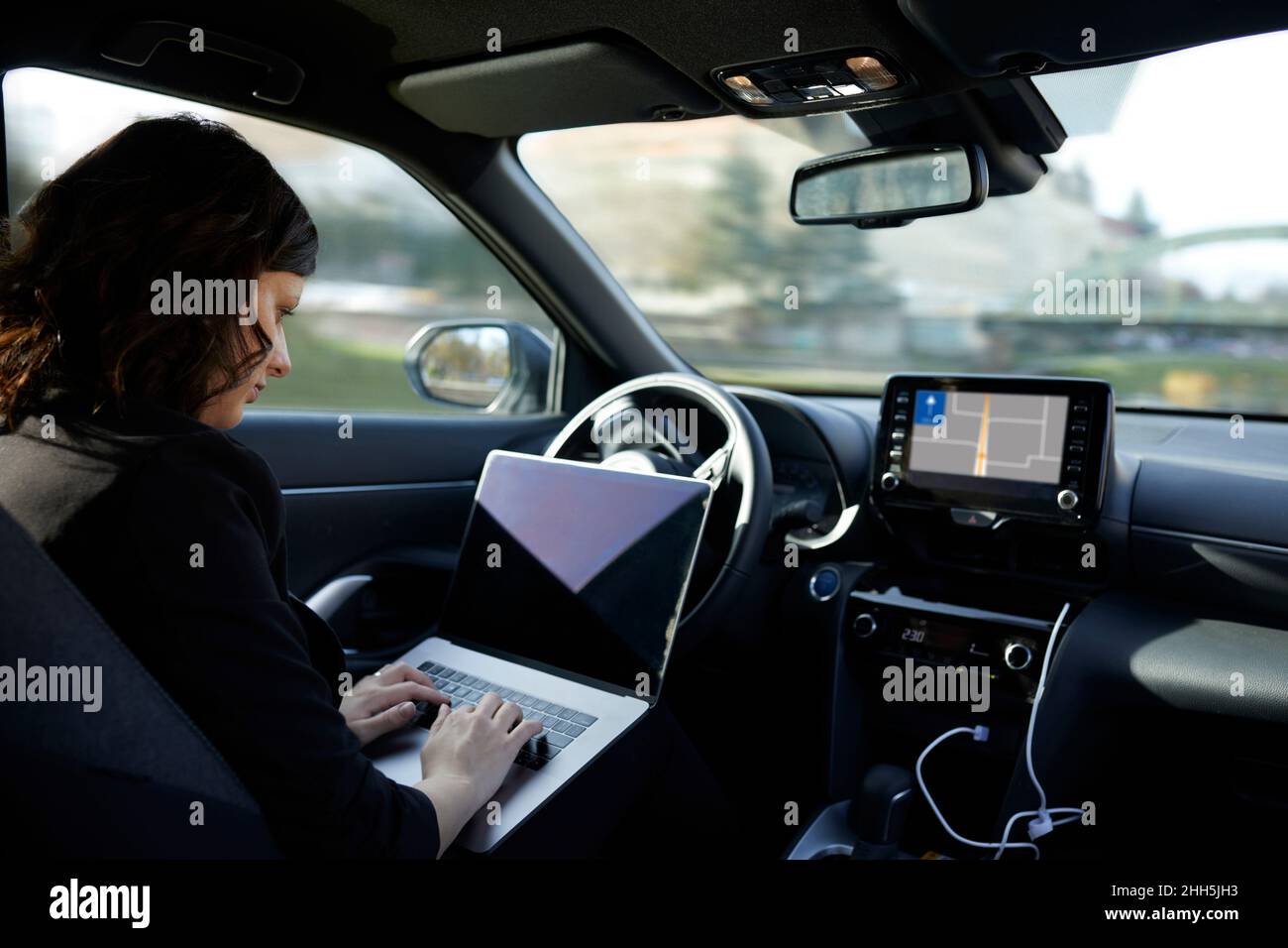 Donna d'affari con notebook che lavora in auto senza conducente Foto Stock