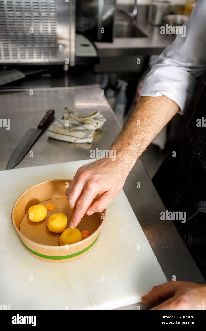 Lo chef prepara il cibo da portare in un contenitore monouso in cucina Foto Stock