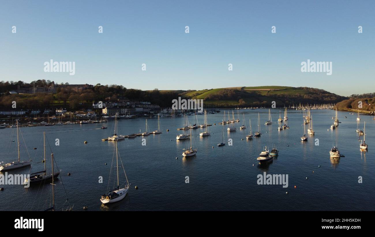 River Dart, Devon, Inghilterra: Barche e yacht ormeggiati alla luce del sole serale in un giorno d'inverno - la città di Dartmouth è sulla sinistra della foto Foto Stock