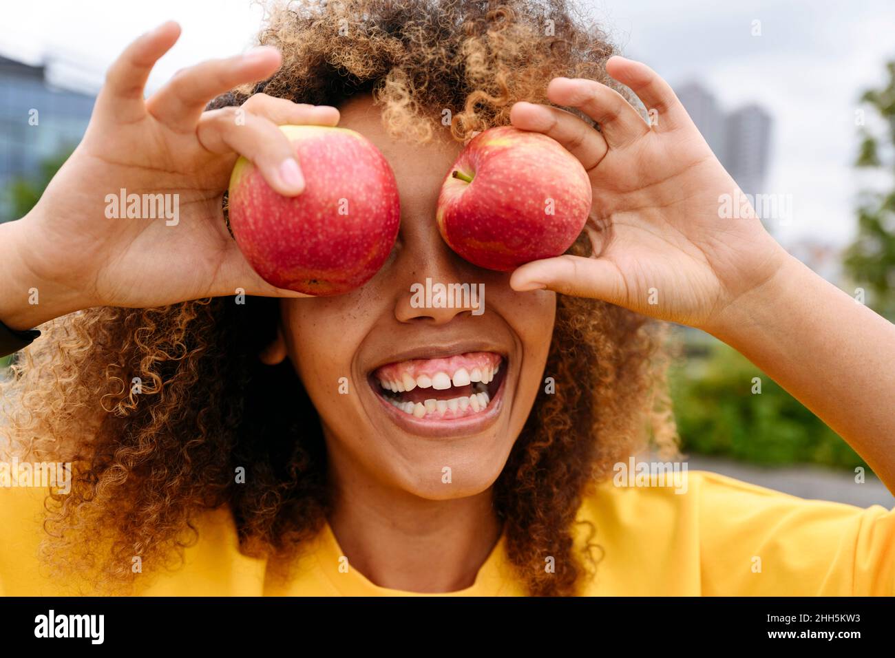Donna allegra che copre gli occhi con le mele Foto Stock