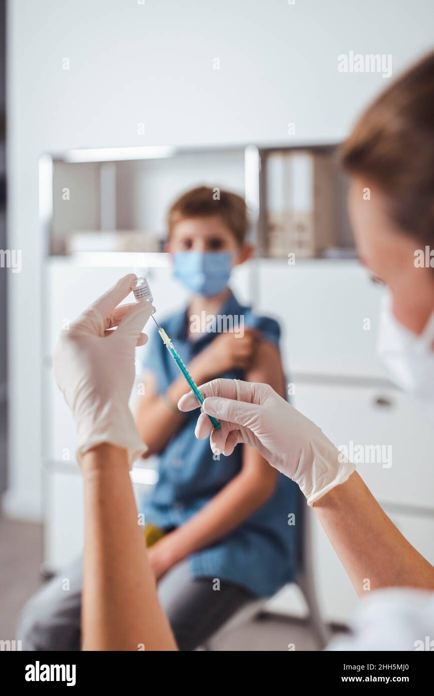 Infermiere preparazione dell'iniezione di vaccino per il ragazzo in background Foto Stock