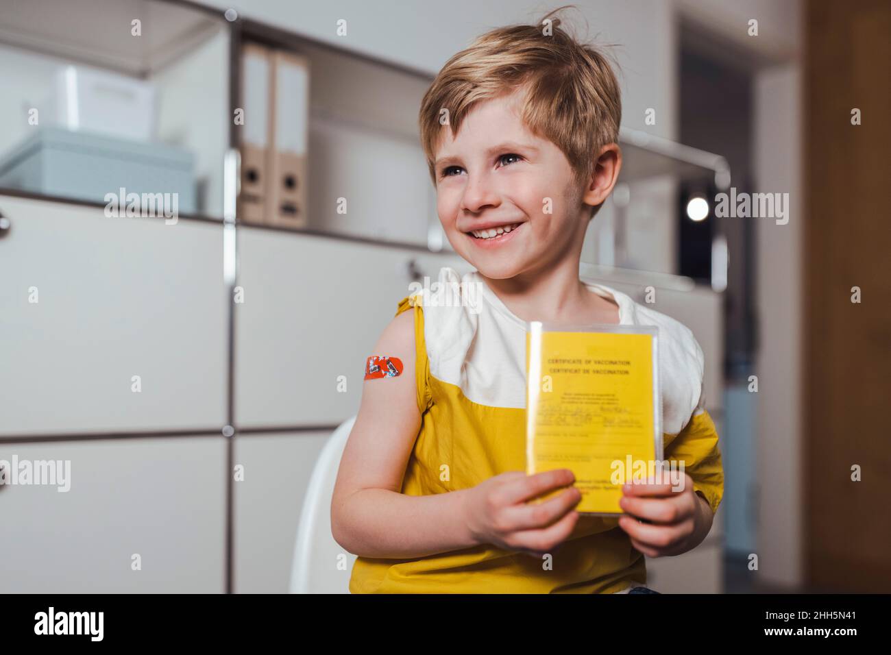 Ragazzo sorridente con certificato di vaccinazione al centro Foto Stock
