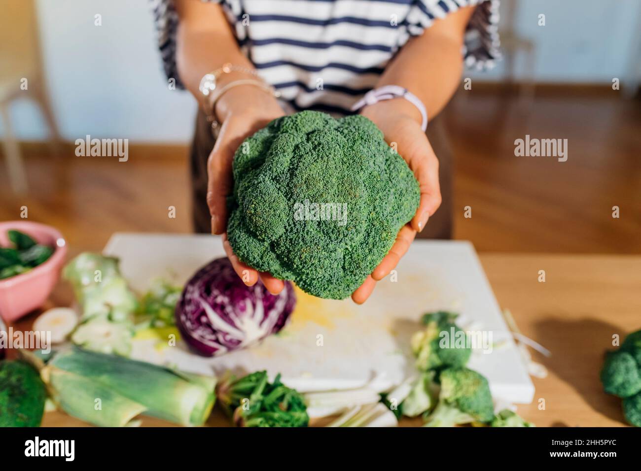 Donna che mostra broccoli freschi a casa Foto Stock