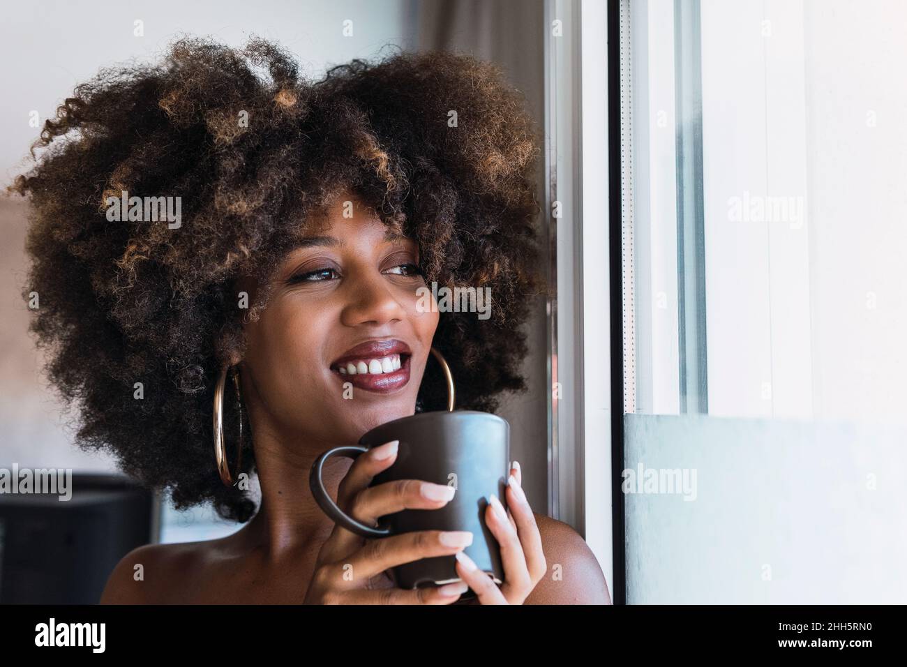 Donna sorridente di bere il caffè a casa Foto Stock