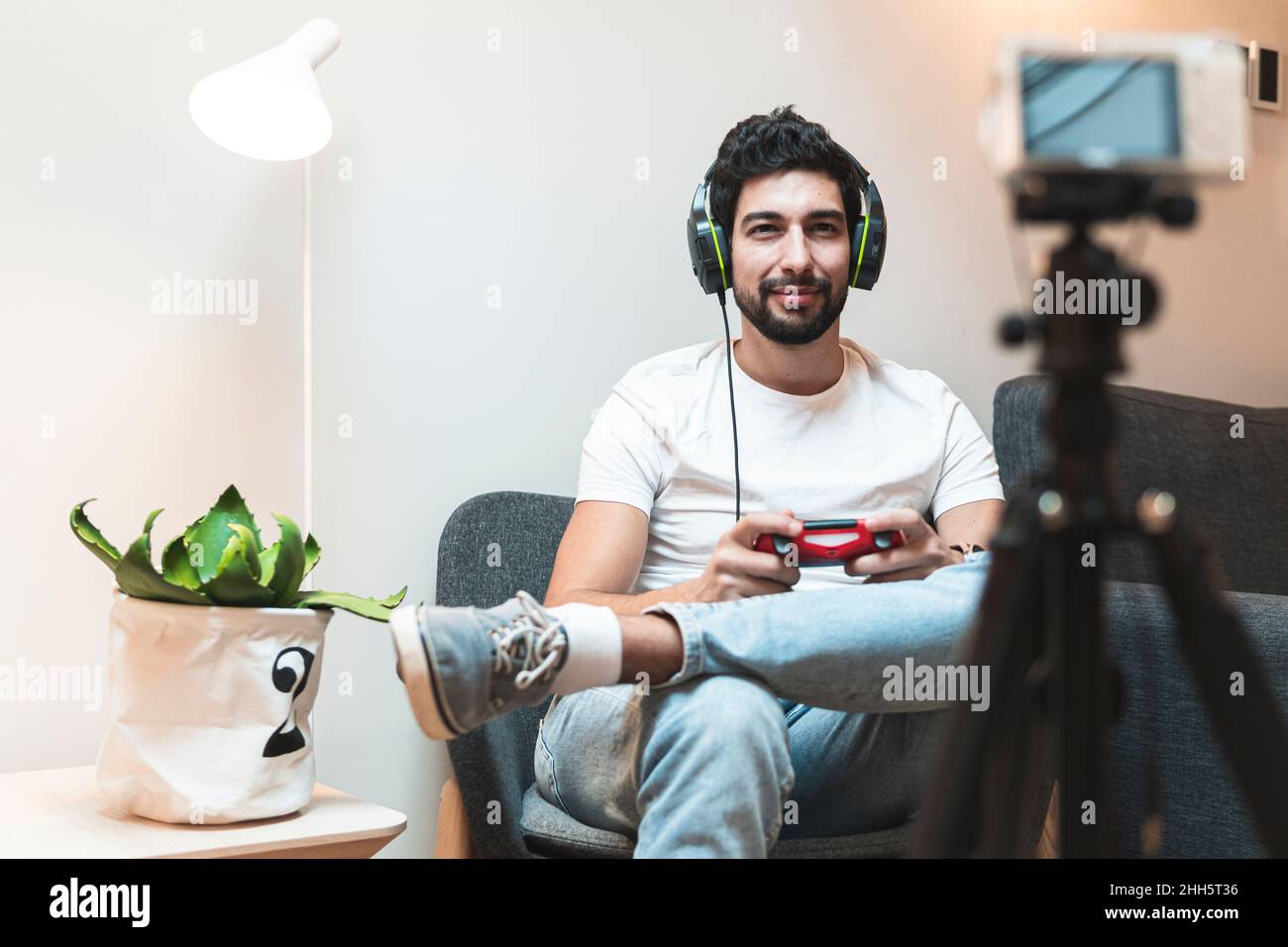 Videogamer con cuffie e controller vlogging attraverso la fotocamera a casa Foto Stock