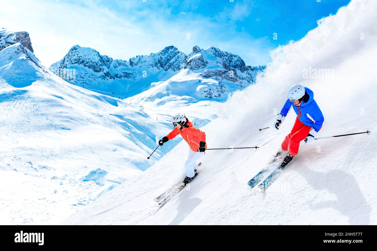 Uomo e donna sciano in discesa sulla montagna innevata di Lech, Austria Foto Stock