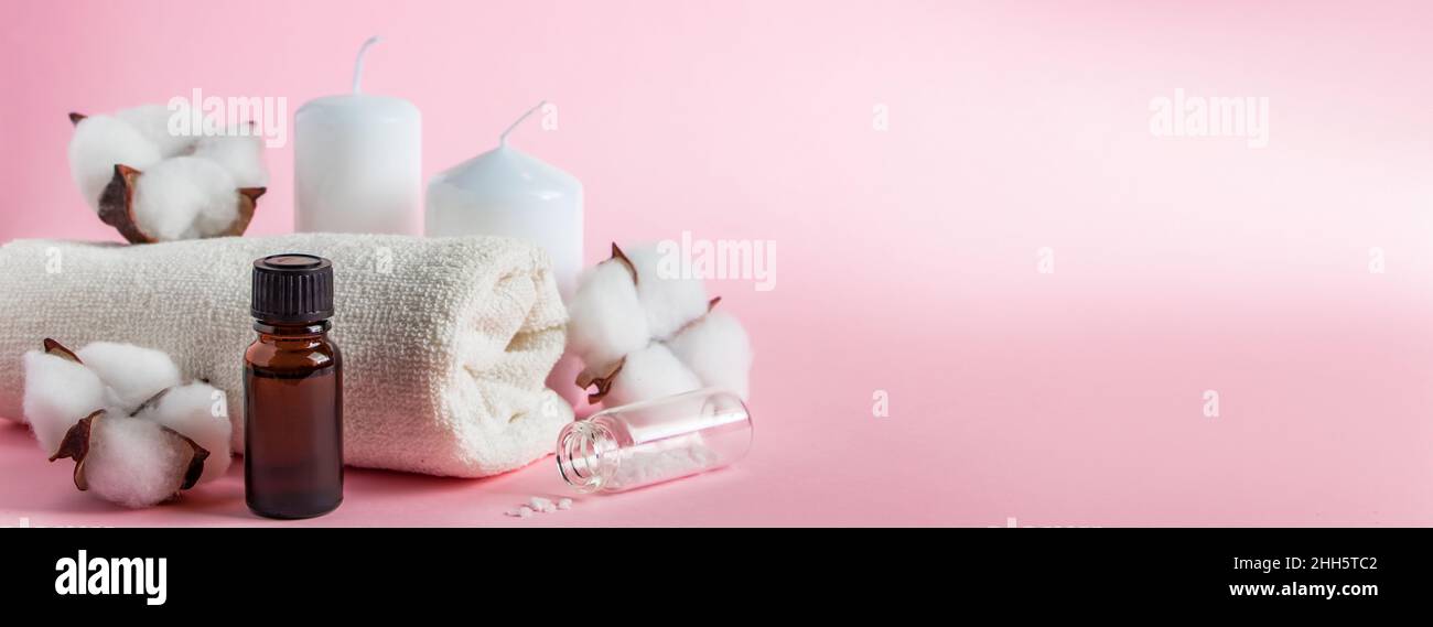 Prodotti cosmetici per spa e aromaterapia. Candele, sale marino, asciugamano e fiori su sfondo rosa. Cura della pelle e concetto di bellezza. Luogo per il vostro te Foto Stock