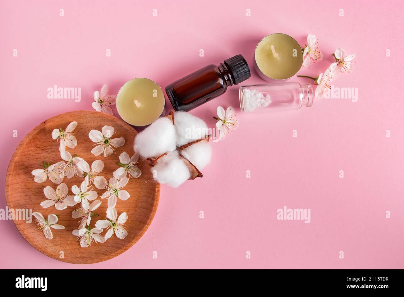 Cura della pelle, spa e concetto di aromaterapia. Prodotti cosmetici naturali su sfondo rosa. Aroma candele e fiori per relax e yoga. Luogo per Foto Stock
