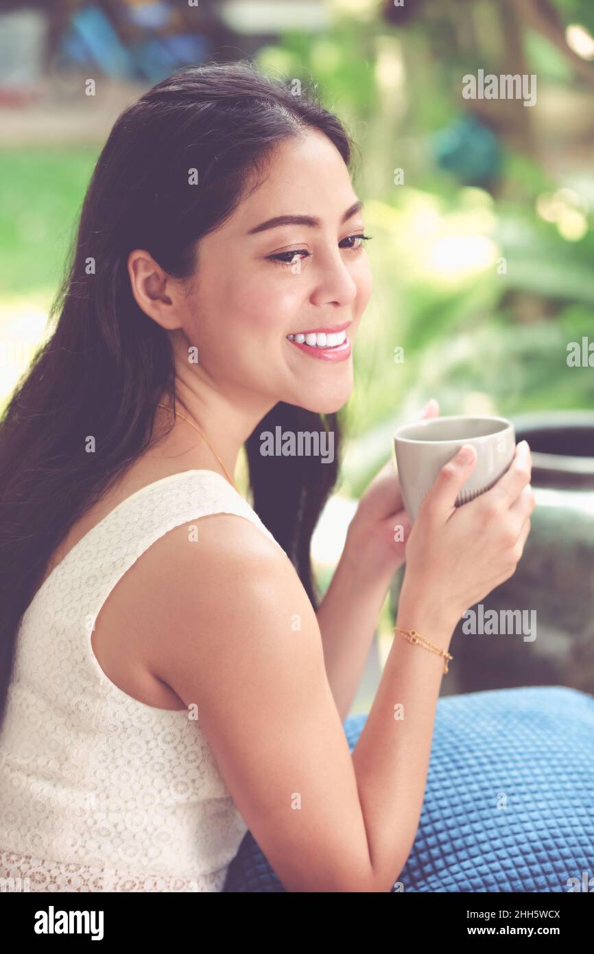 Lo stile di vita della bella donna asiatica gode di caffè fresco al mattino a casa. Tempo felice della vita cittadina. Tono vintage. Foto Stock