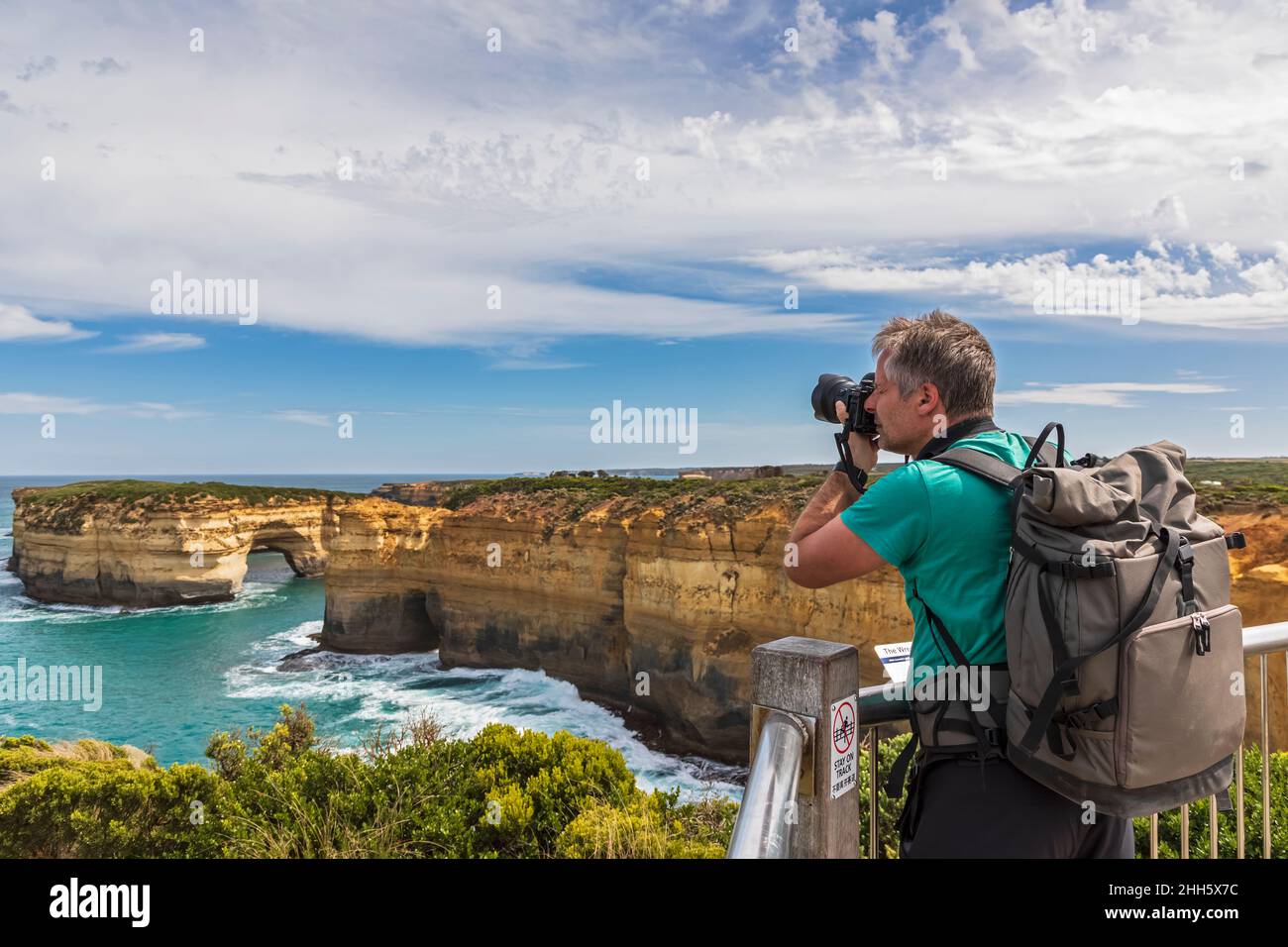 Australia, Victoria, turista maschile fotografando arco naturale a Loch Ard Gorge Foto Stock