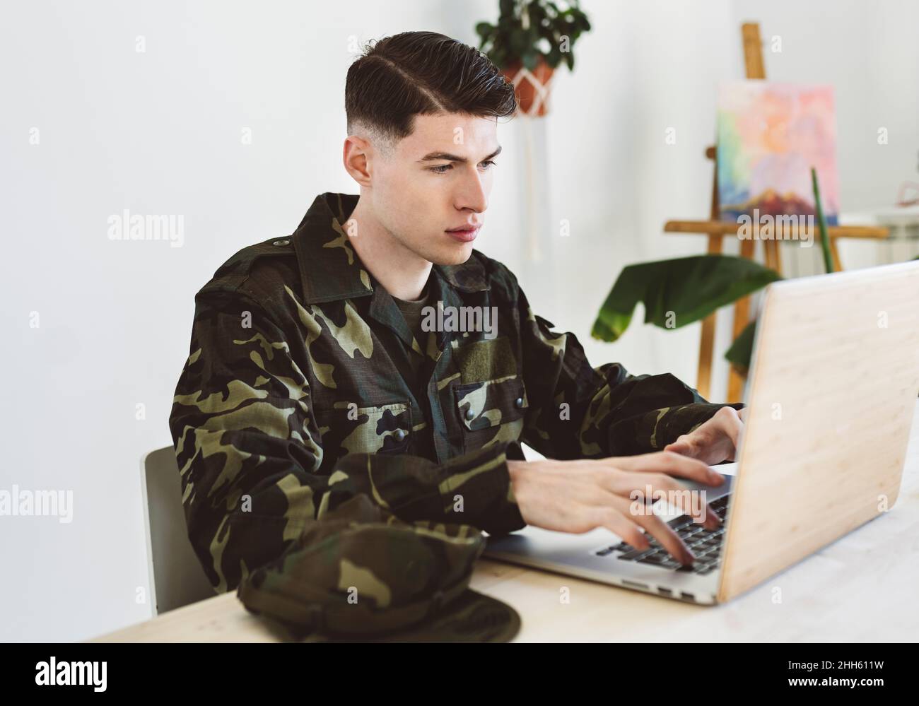 Giovane uomo dell'esercito che usa un computer portatile a casa Foto Stock
