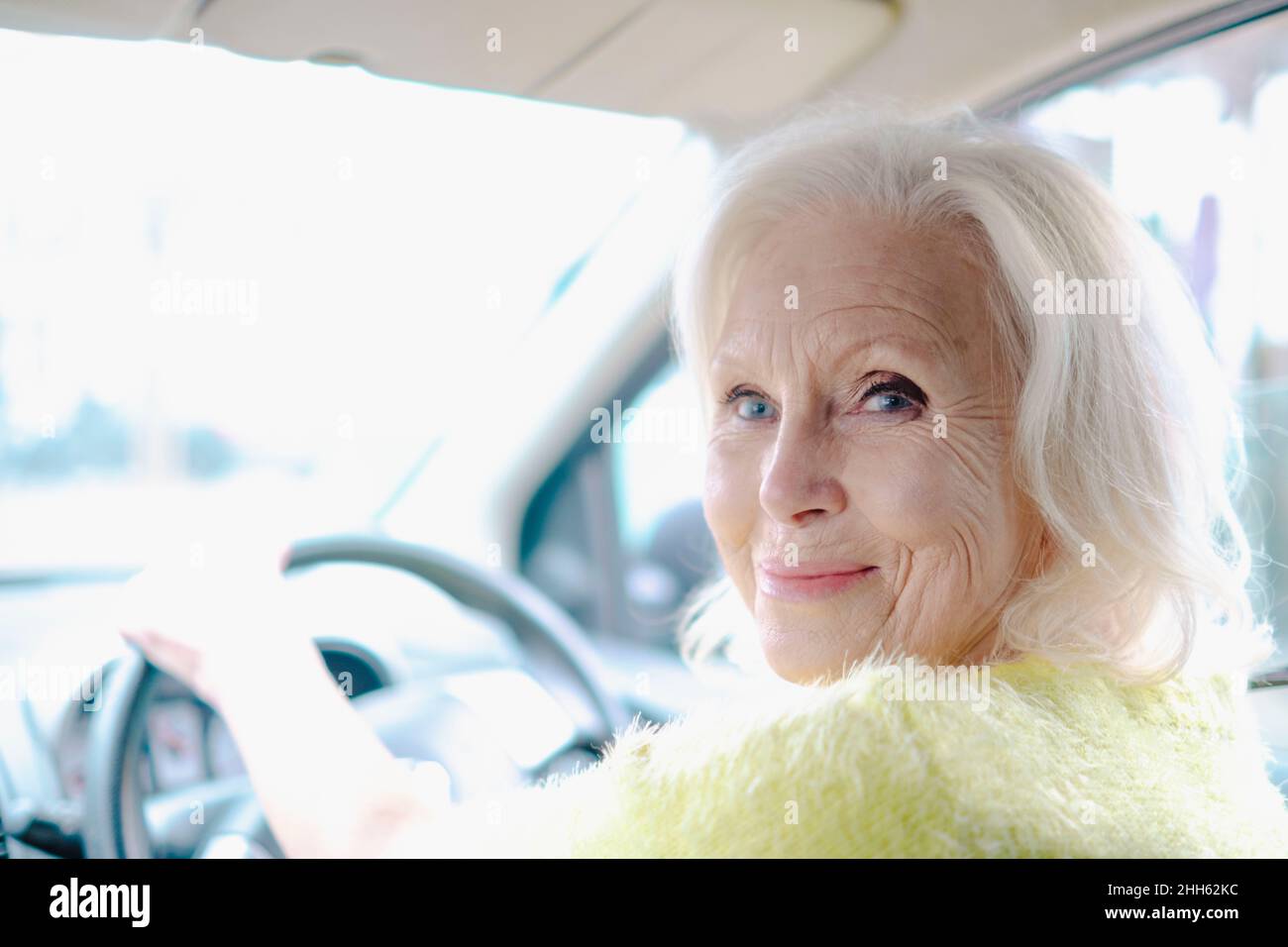 Donna anziana in pensione che guarda oltre la spalla all'interno dell'auto Foto Stock