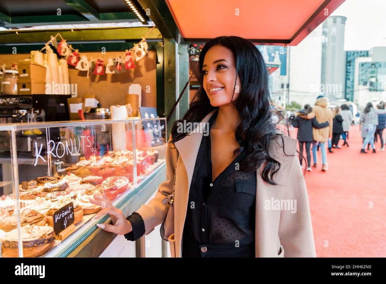 Donna sorridente che acquista cibo dolce dal negozio nel mercato di Natale Foto Stock