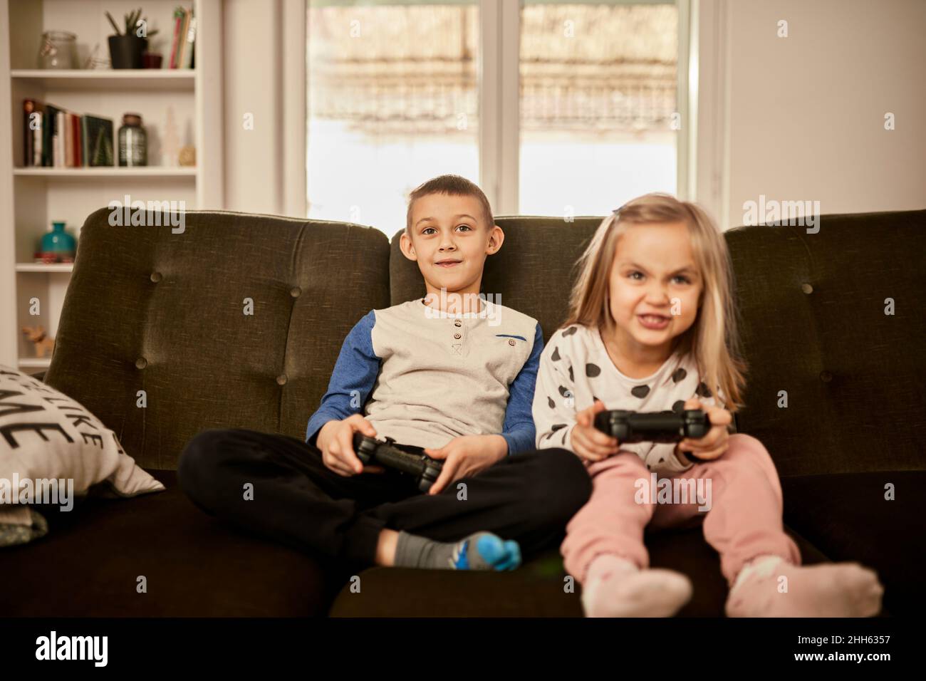 Fratello e sorella giocare video gioco seduto sul divano a casa Foto Stock