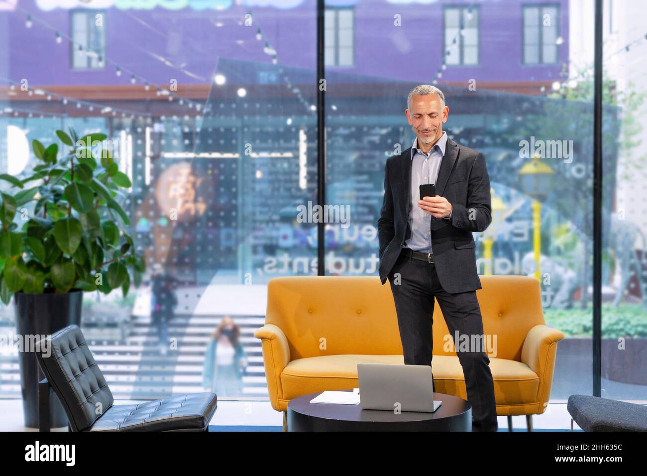 Messaggi di testo per uomini d'affari sul telefono cellulare nella hall Foto Stock