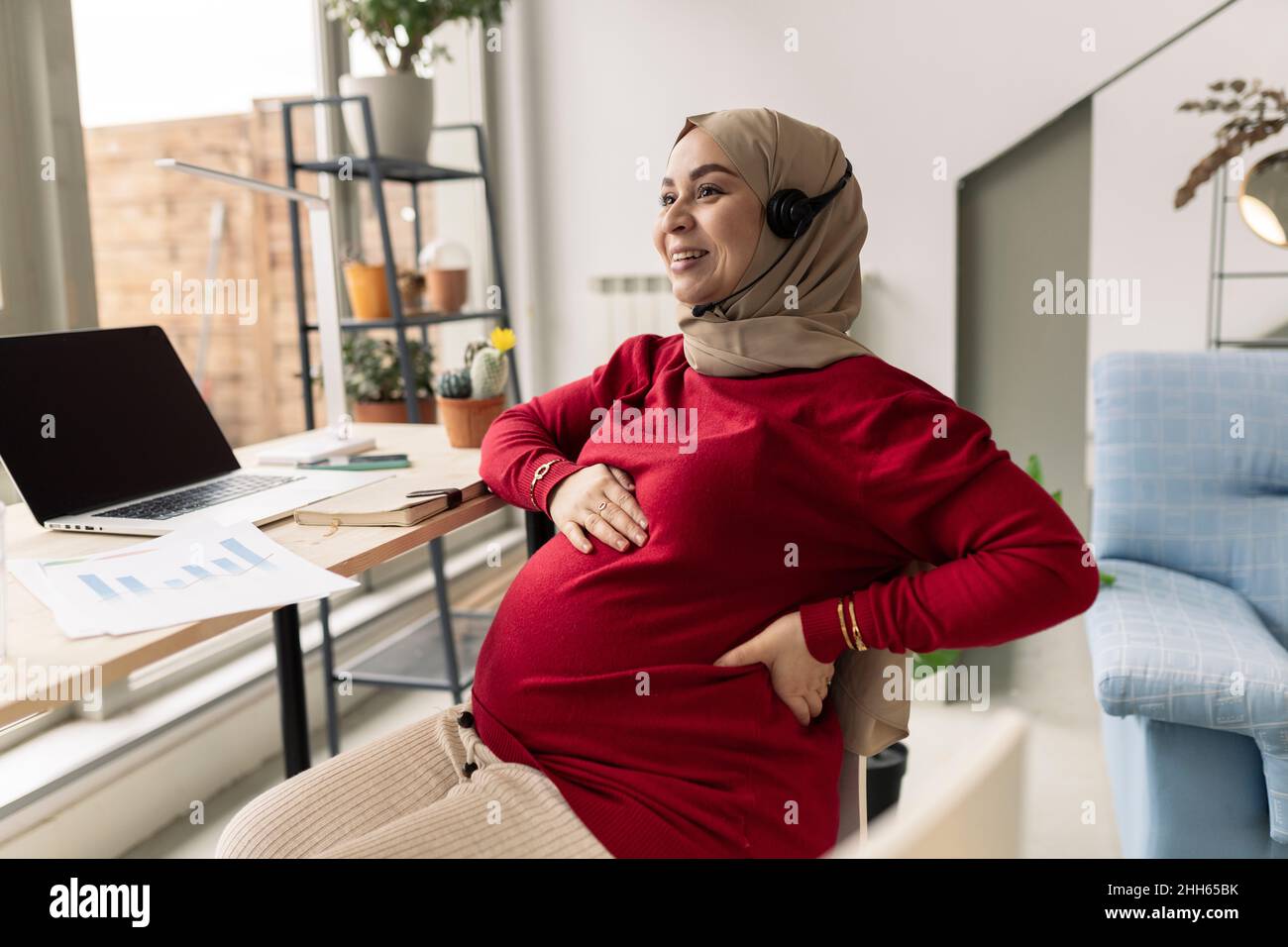 Sorridente donna d'affari incinta che libera a casa Foto Stock