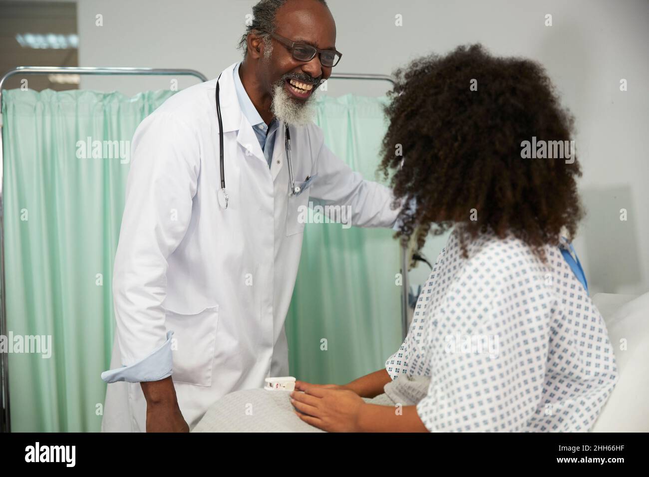 Buon medico che guarda il paziente che indossa l'ossimetro in ospedale Foto Stock