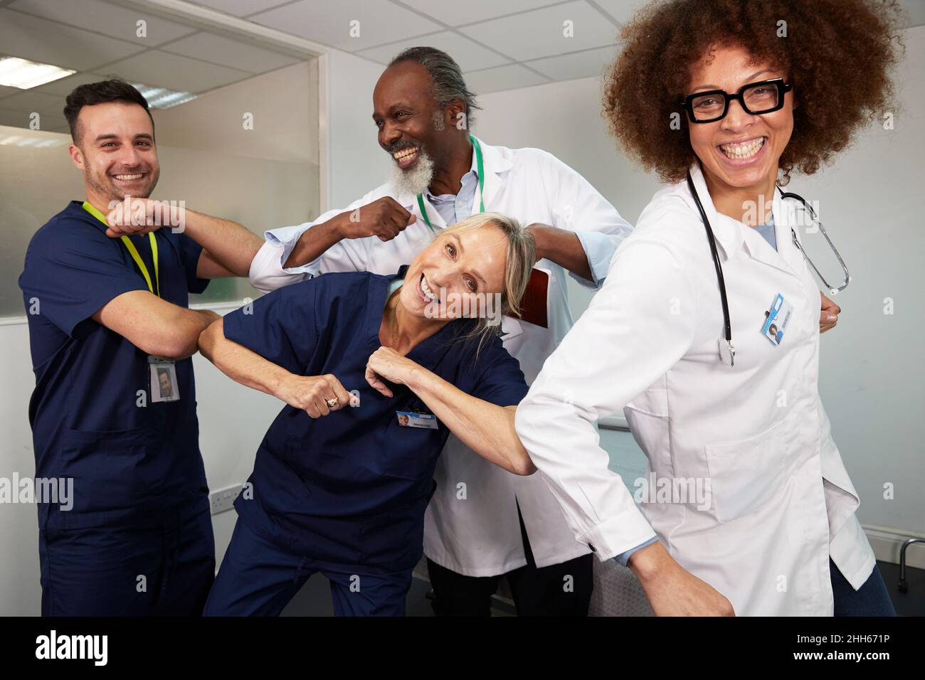 Operai medici multirazziali giocosi che danno i colpi del gomito a vicenda all'ospedale Foto Stock