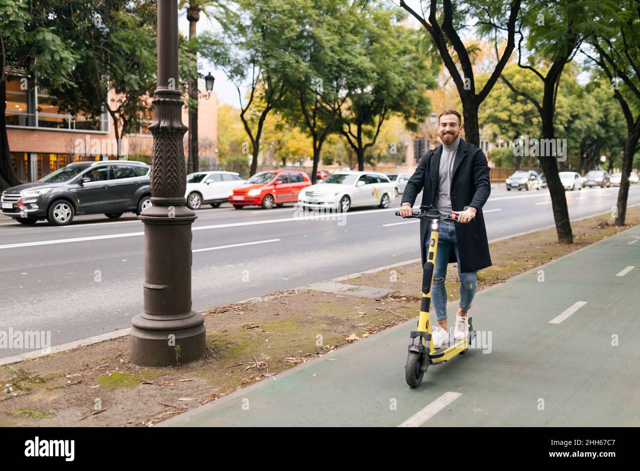 Uomo che guida scooter elettrico a spinta in strada in città Foto Stock