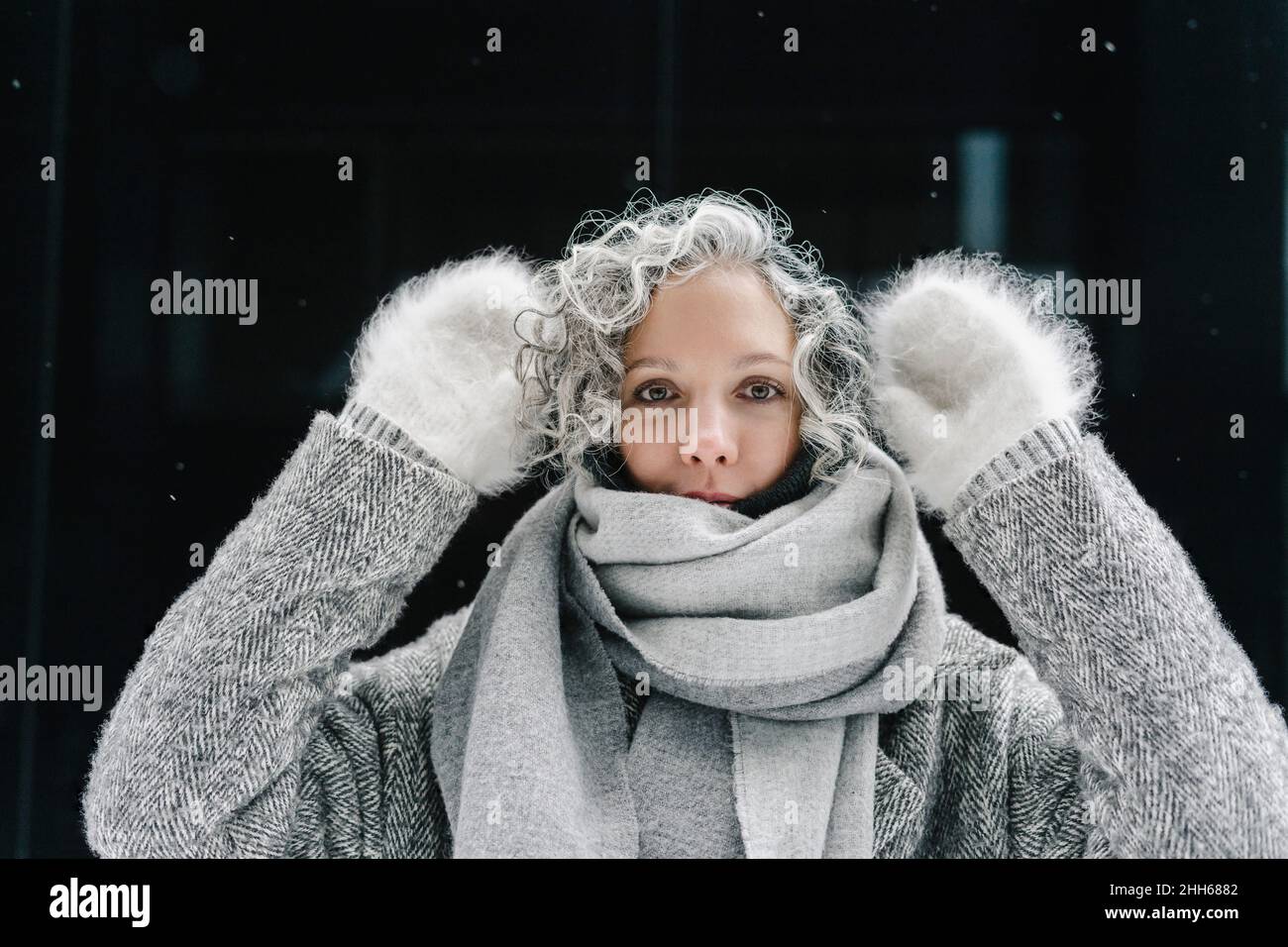 Donna con capelli ricci grigi indossando guanti in pelliccia Foto Stock