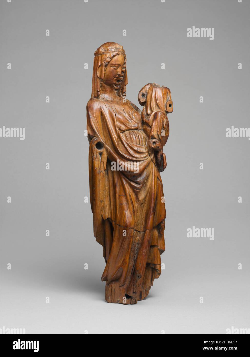 Vergine e Bambino ca. 1300 Francese del Nord scolpito interamente nel tondo, la statuetta impressiona dalla delicatezza della sua esecuzione e dal suo carattere monumentale. Lo scultore introdusse correzioni ottiche per accogliere un punto di vista basso, come da un prie-dieu (l'occhio sinistro della Vergine è leggermente più alto dell'occhio destro, in modo che quando visto da sotto entrambi gli occhi rimangono visibili e appaiono focalizzati sul Bambino). La superficie, indossata da baci e carezze, attesta l'intimo rapporto del devoto con immagini durante il Medioevo. Vergine e Bambino. Francese del Nord. CA. 1300. Legno di bosso. Scultura-legno Foto Stock