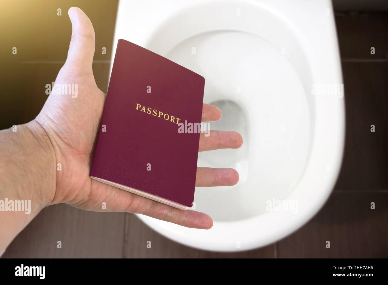 La mano tiene il passaporto del cittadino sopra il gabinetto, getta fuori il suo passaporto. Concetto - cambiamento di cittadinanza, perdita del passaporto, problemi politici, infr Foto Stock
