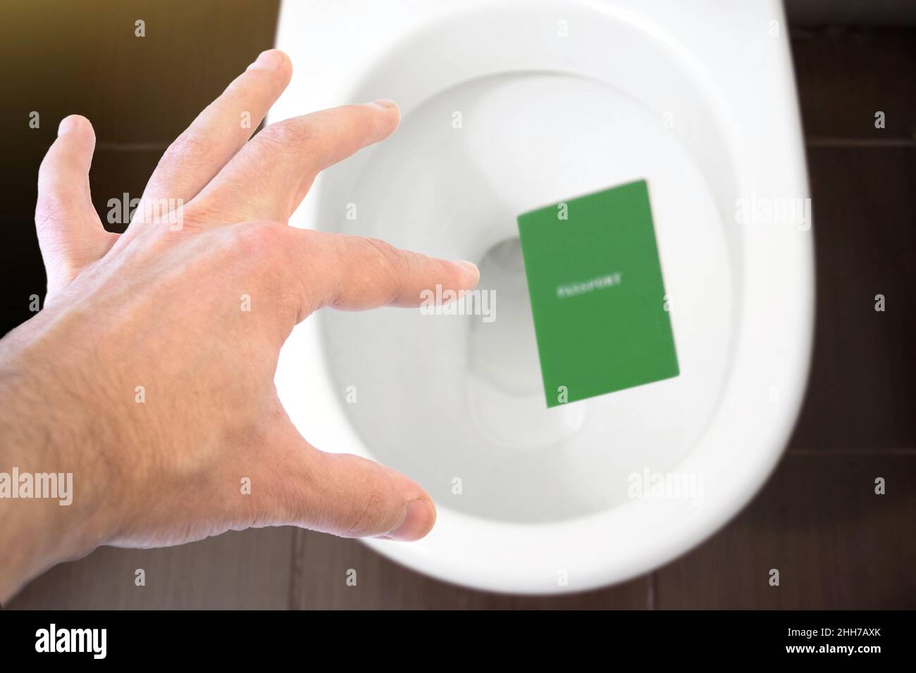La mano tiene il passaporto del cittadino sopra il gabinetto, getta fuori il suo passaporto. Concetto - cambiamento di cittadinanza, perdita del passaporto, problemi politici, infr Foto Stock