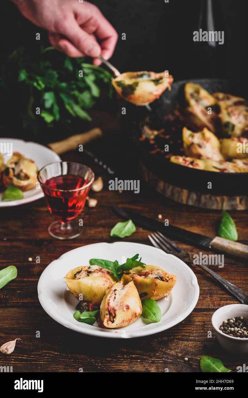 Conchiglie di jumbo al forno farcite con manzo macinato, spinaci e formaggio su piatto bianco Foto Stock