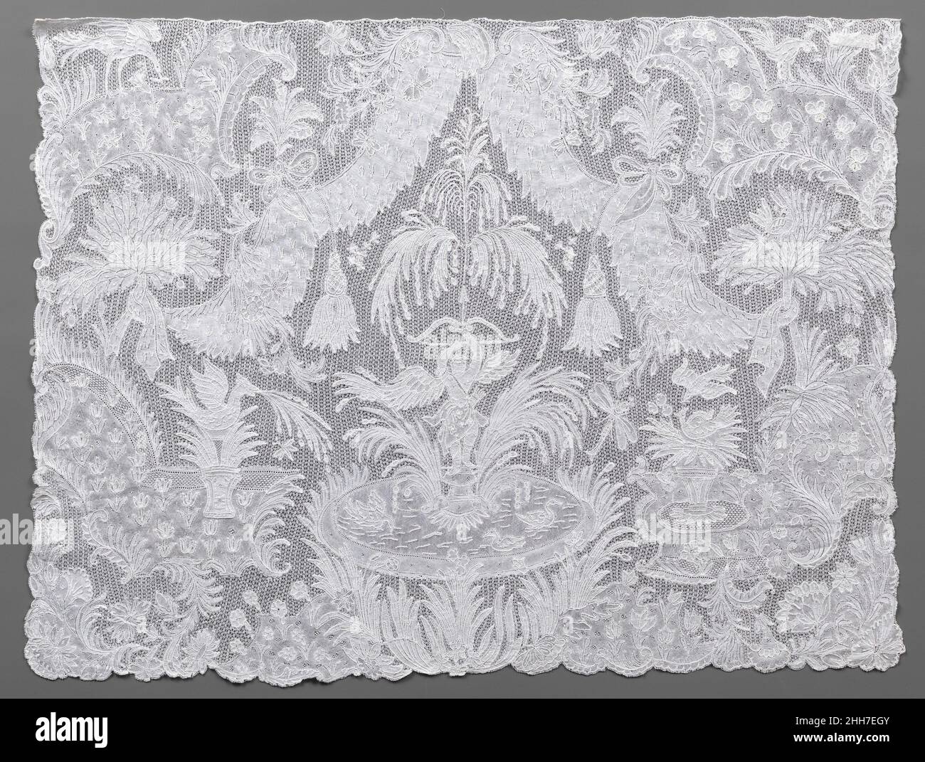 Cravat fine metà del 18th secolo fiammingo, Brussels pannelli in pizzo figurato come questo erano oggetti di genere di alta moda collana, destinato ad essere fissato alla fine di un lungo, fine tessuto cravat. Le immagini elaborate, lunghe da realizzare, hanno reso i pannelli accessori estremamente costosi. Ispirandosi ai giardini formali contemporanei, il design di questo esempio si basa su una fontana con getti d'acqua che emettono dalla punta della freccia sollevata di Amor e cadono per riempire un bacino per nuotare gli uccelli. Tra i parterres piantati con tulipani e altri fiori si trova una fontana a forma di Foto Stock